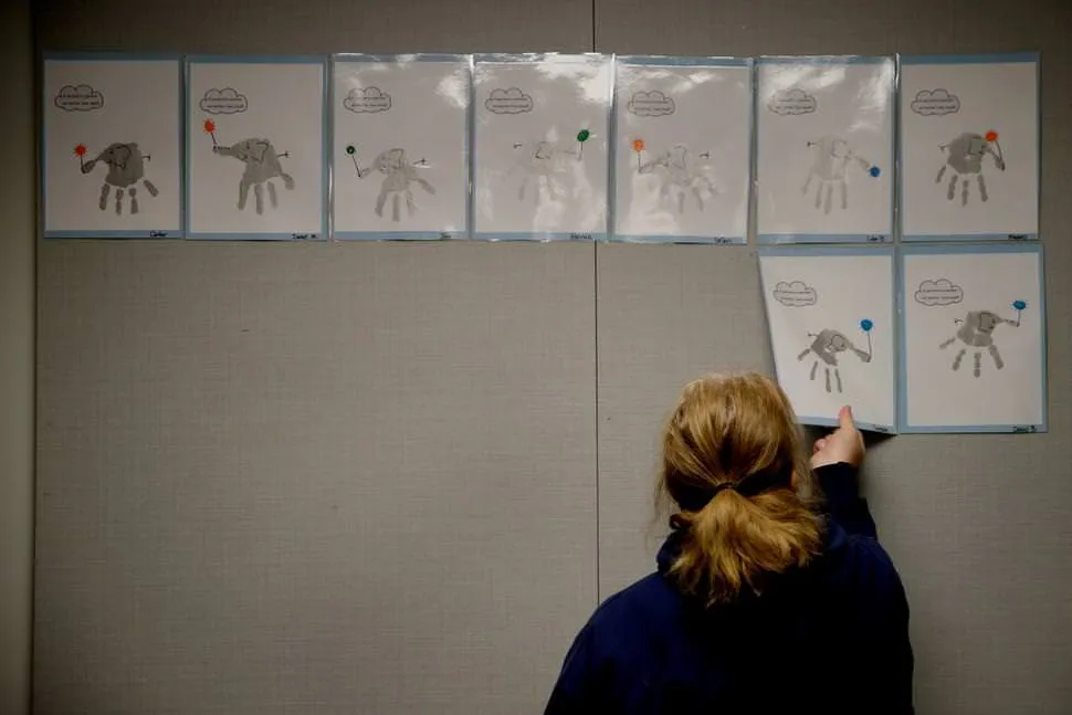 FILE - In this May 12, 2020, file photo, a teacher removes students’ artwork from a bulletin board as she packs the art in her kindergarten classroom at an elementary school in Olathe, Kan. The coronavirus is proving ruinous to state budgets, forcing many governments to consider once-unthinkable cuts to schools, universities, health care programs and a wide array of other basic functions. (AP Photo/Charlie Riedel, File) THE ASSOCIATED PRESS