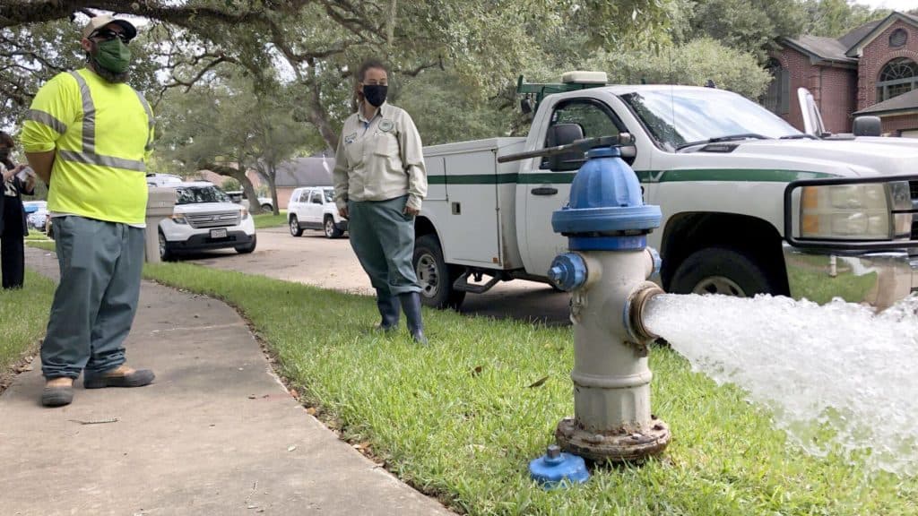 City workers Kristina Watson, right, and Lennie Miner, a maintenance foreman monitor Monday, Sept. 28, 2020, test water flowing out of a hydrant in Lake Jackson, Texas.  (AP Photo/Jim Mone)